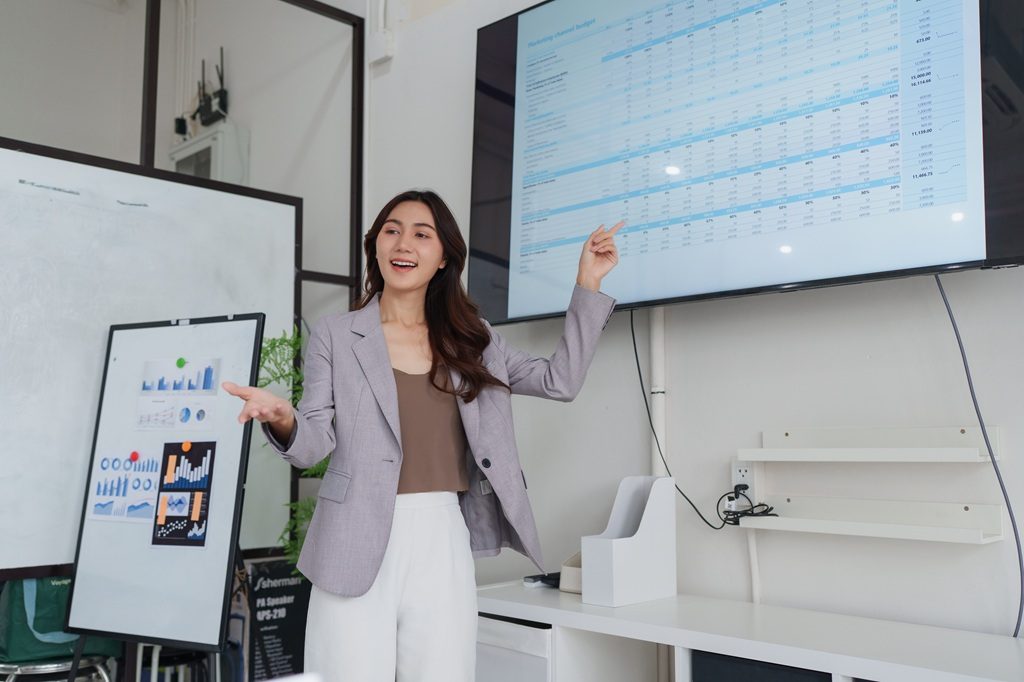 A female executive presenting financial data on large screen using MS Excel