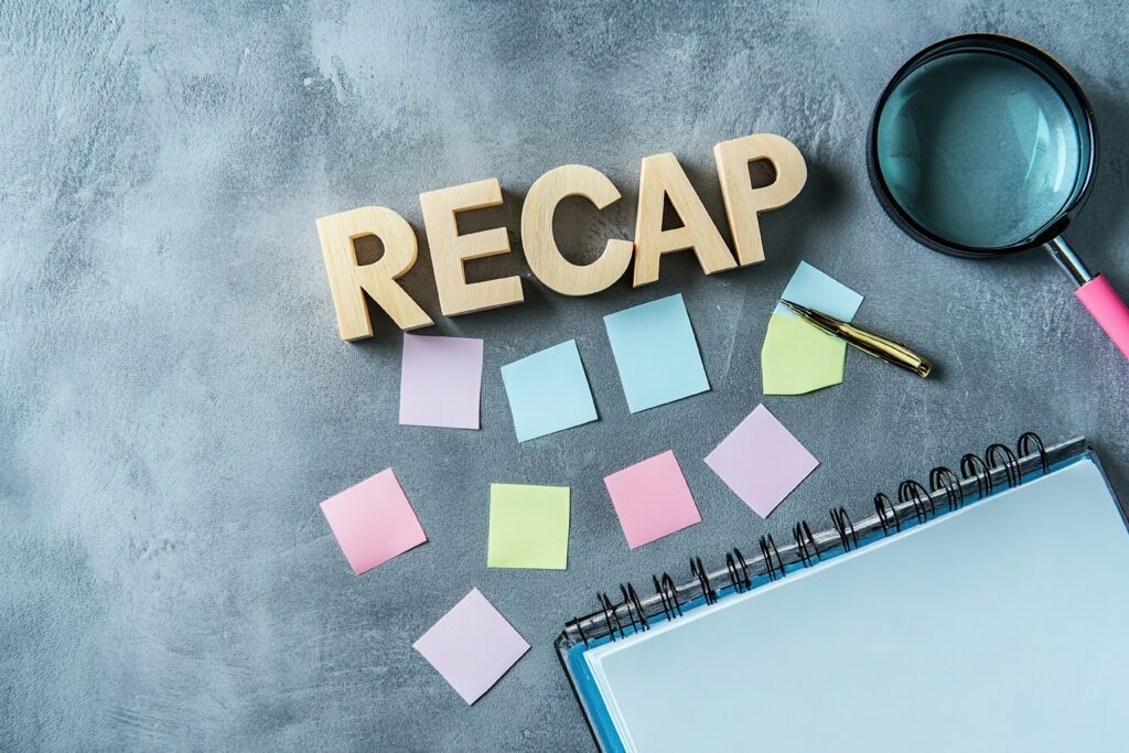 A binder notebook,, magnifying glass, several multi-colored Post-It notes, the word RECAP spelled out in wooden letters
