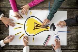 Research and Development (R&D) - Image of a group of men and a woman drawing a yellow light bulb