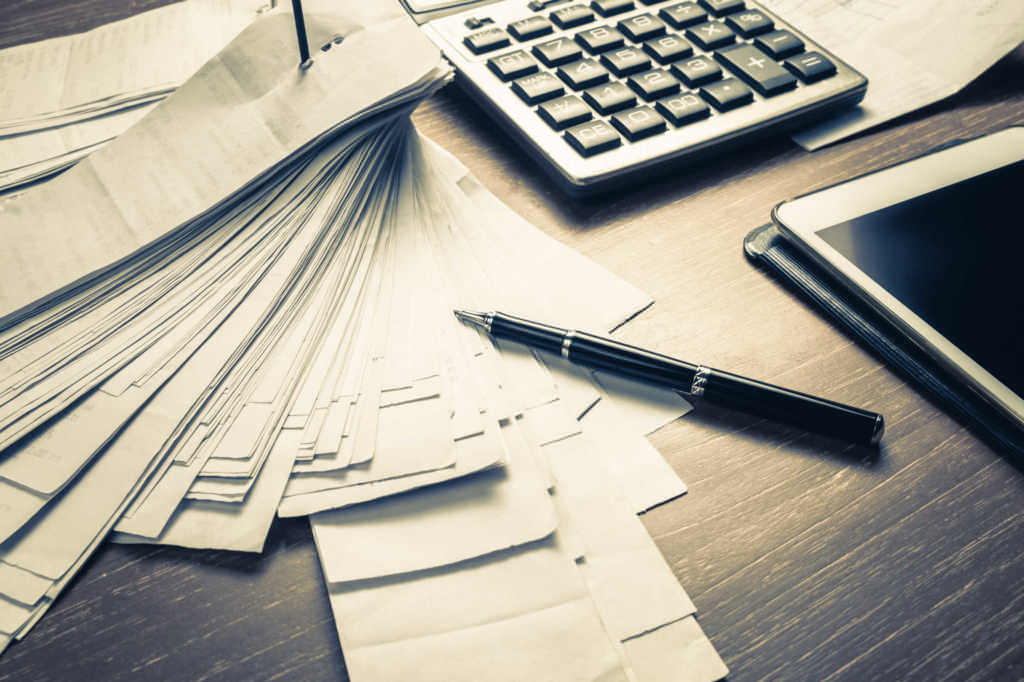 Source Documents - Image of a pile of receipts next to a pen, calculator, and tablet 